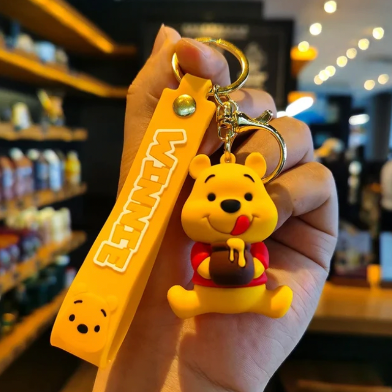 Winnie the Pooh 3D PVC figure keychain held in hand with yellow Winnie branded wrist strap