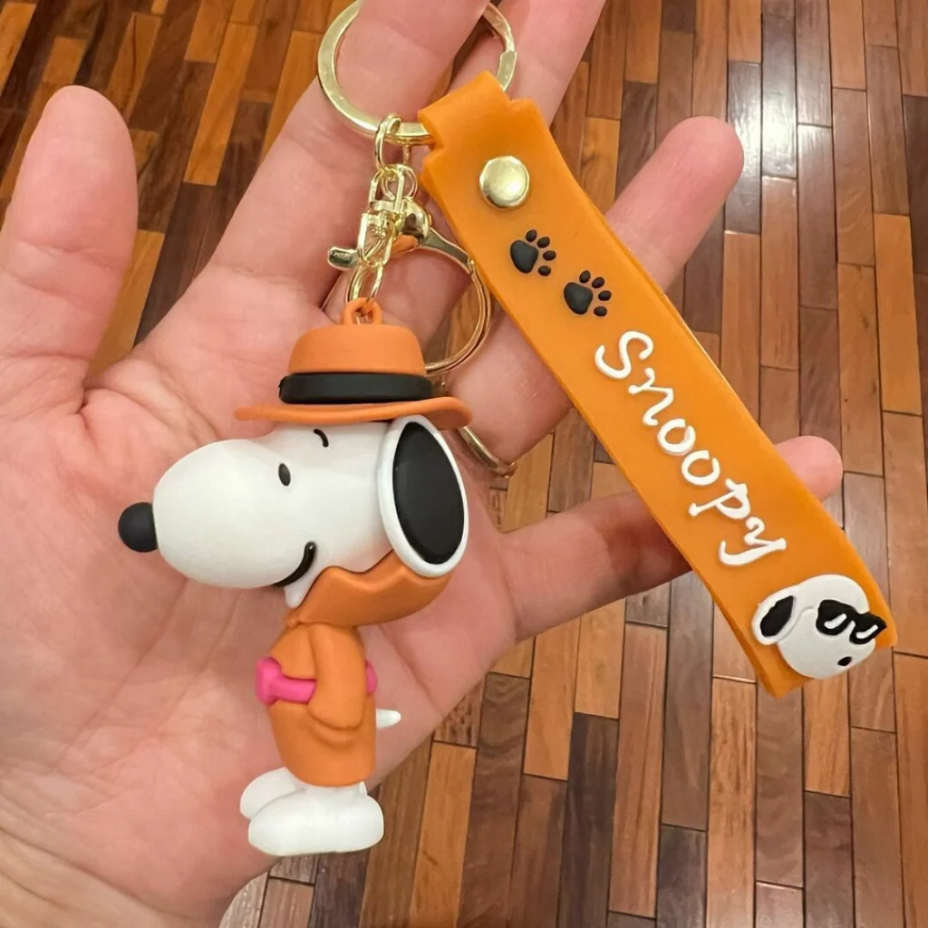 Snoopy orange outfit 3D PVC keychain held in hand showing figure detail
