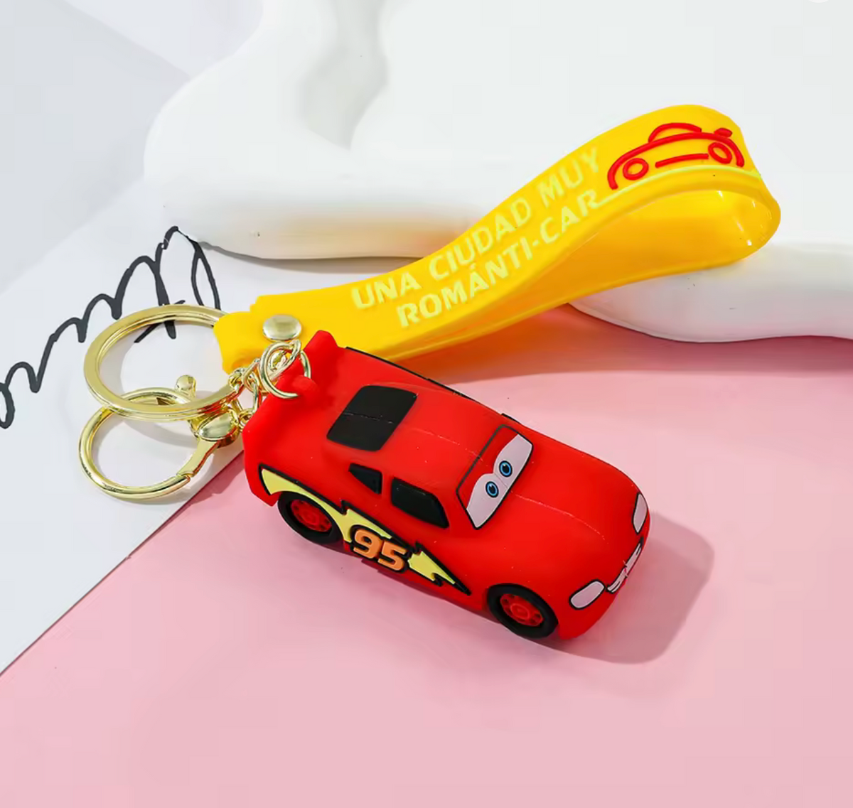 Lightning McQueen keychain front view with yellow wrist strap on pink background